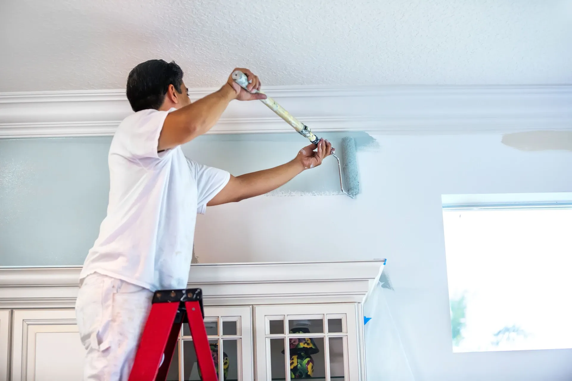 Decorator rolling a fresh even coat onto a wall